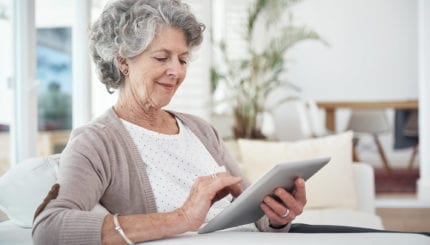 elderly woman reading using a tablet