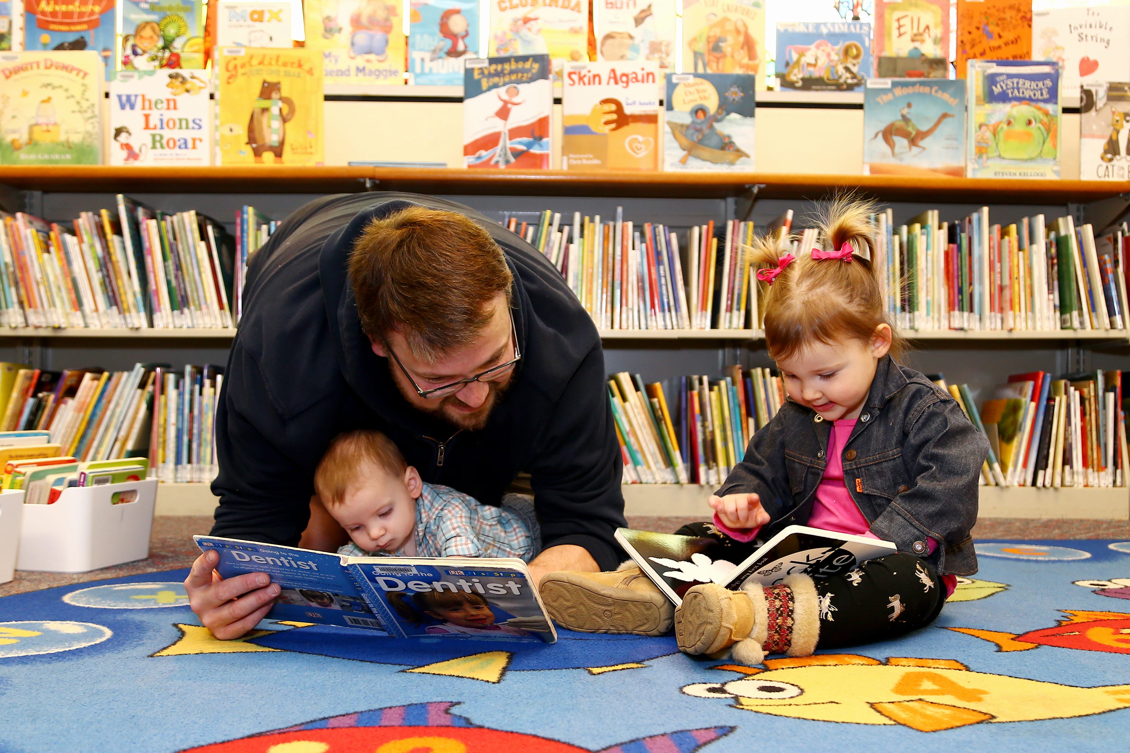 Man reading to baby and preschool child